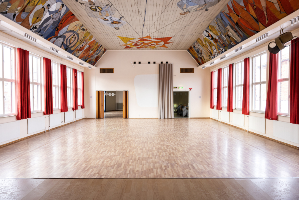 Evenemangslokal Albrektssalen: Allrum med höga fönster, röda gardiner och målning i taket.