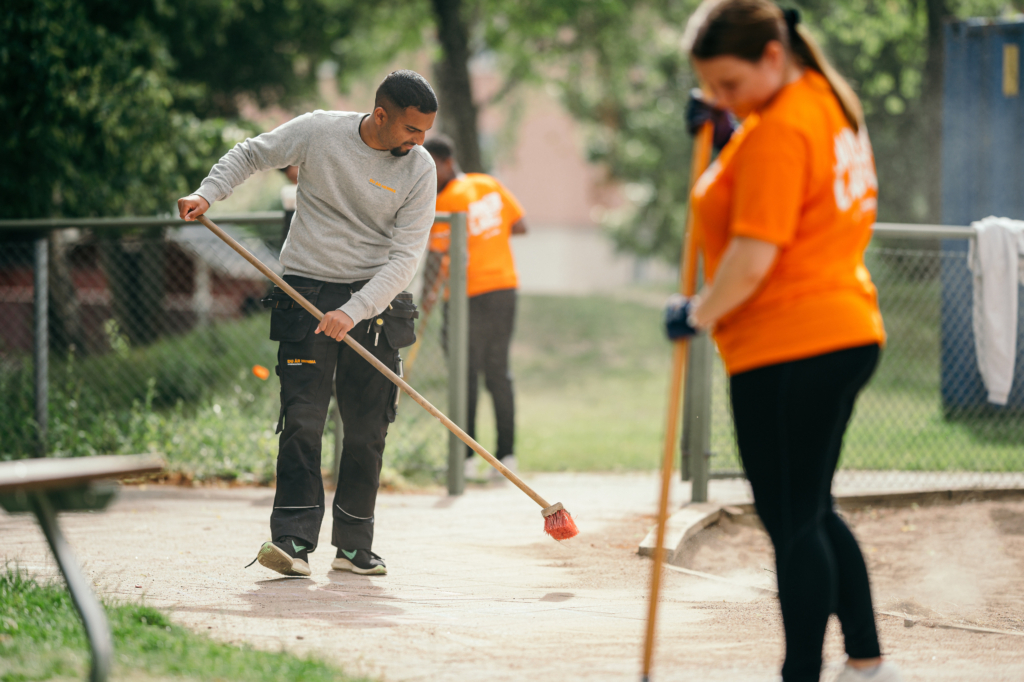Två ungdomar utför yttre skötsel i ett område.