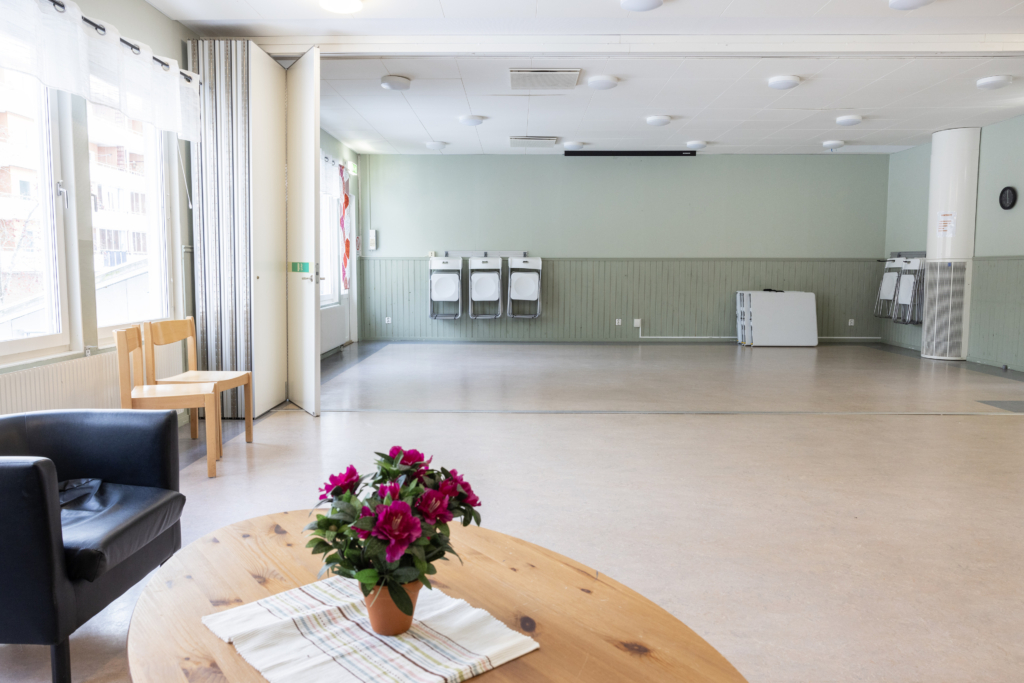 Kvarterslokal Mässen: Allrum med vikbar rumsavdelare, soffgrupp samt stolar och bord.