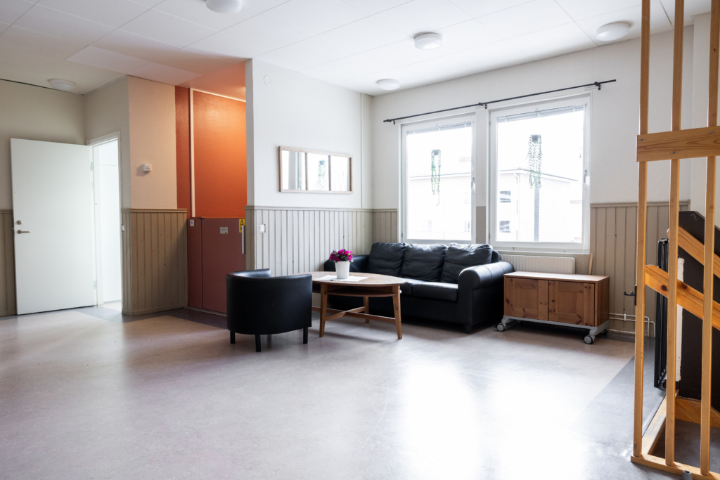 Kvarterslokal Mässen: En tvåsitssoffa och fåtölj med soffbord i korridorutrymme.