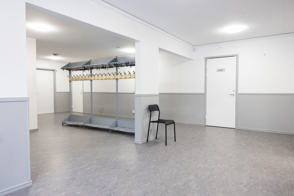 Kvarterslokal Nocken: kapprum med klädställning och dörr till förrådet.