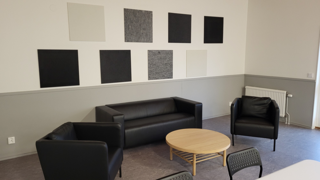Kvarterslokal Nocken: Allrum med svarta lädermöbler och ljudabsorbenter på väggen