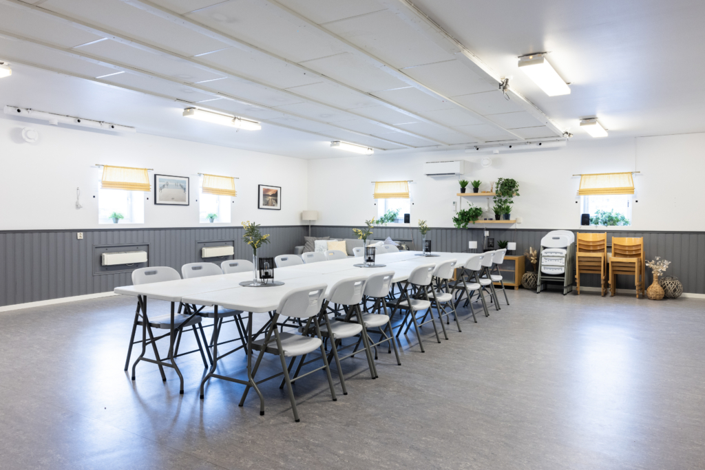 Kvarterslokal Tinget: Allrum med grå bröstpanel och bord och stolar.