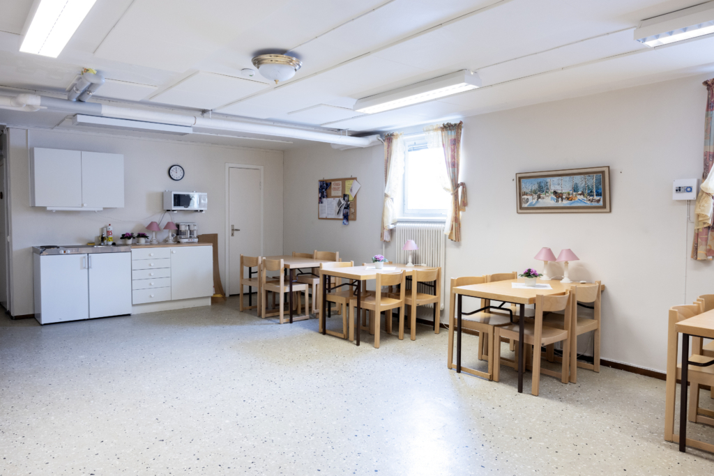 Kvarterslokal Västra Lund: Allrum med bord och stolar samt en kokvrå med diskbänk, kyl och micro.