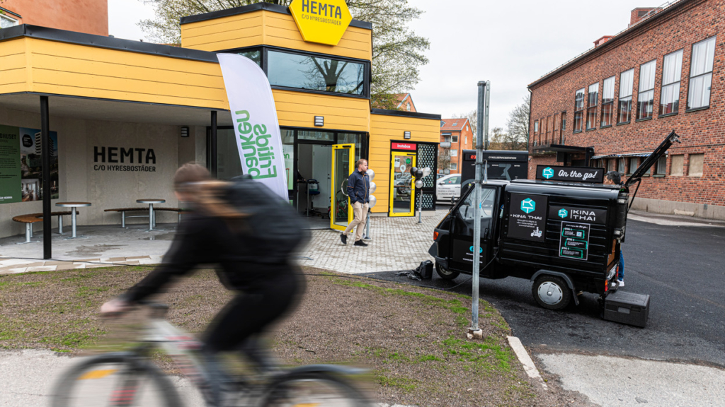 En person cyklar förbi den gula byggnaden Hemta.