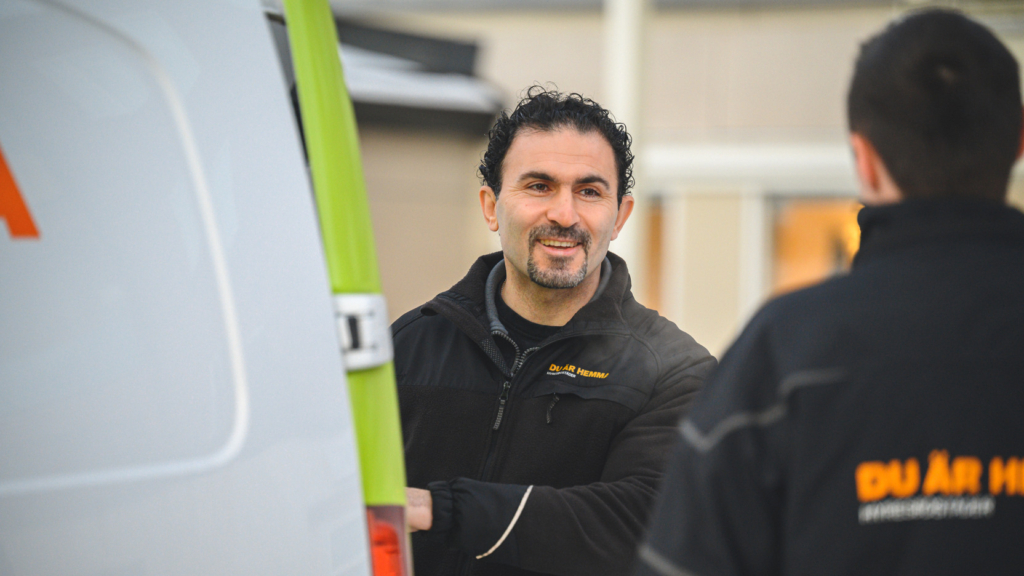 Två medarbetare på Hyresbostäder står vid en servicebil och pratar med varandra.