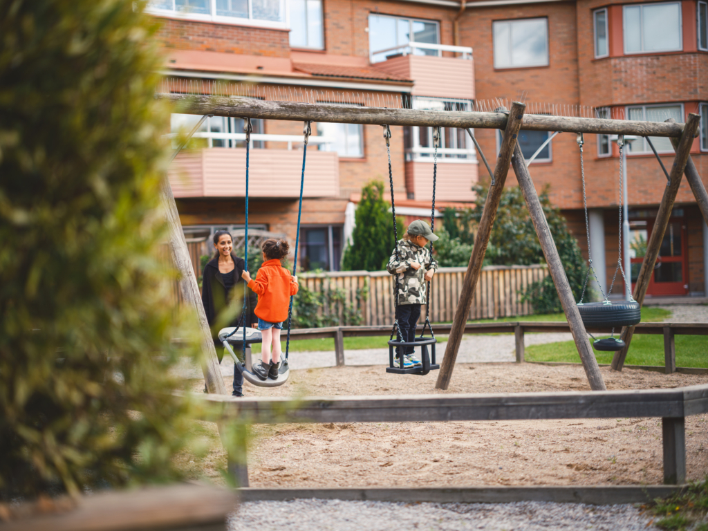 Två barn som gungar i en lekpark.