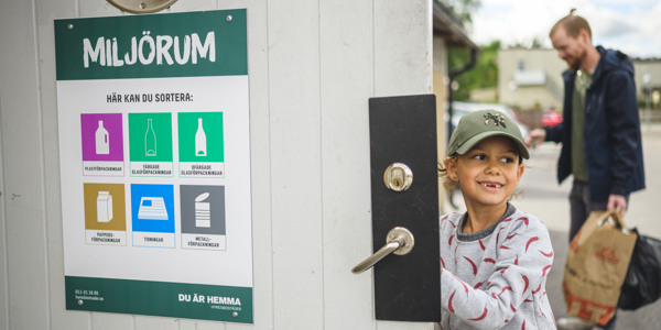 Ett barn öppnar dörren till ett miljörum för att källsortera.