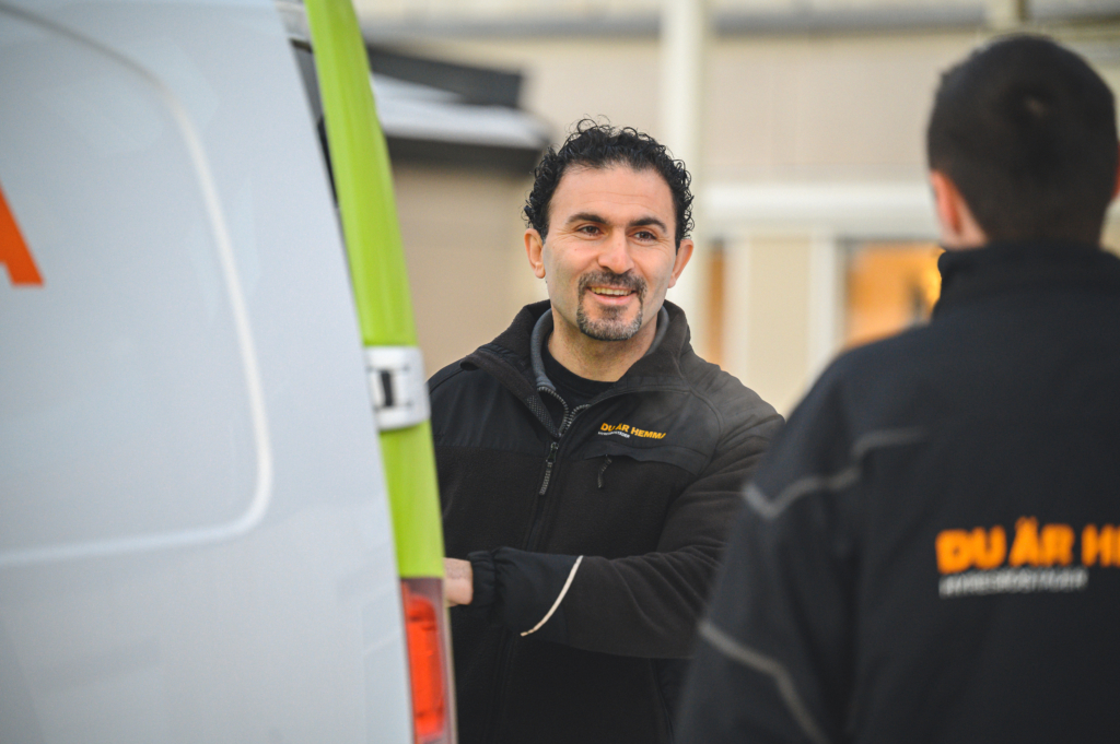 En manlig anställd på Hyresbostäder stänger en skåpbil och pratar med en annan anställd.