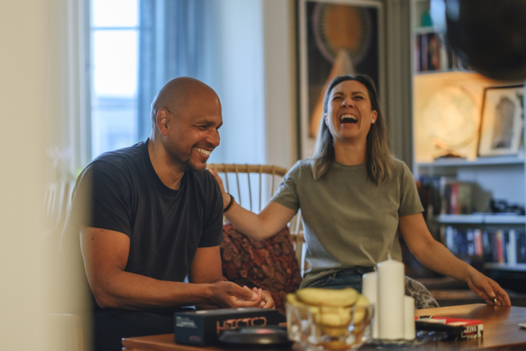 En man och en kvinna sitter vid ett vardagsrumsbord och spelar spel tillsammans. 