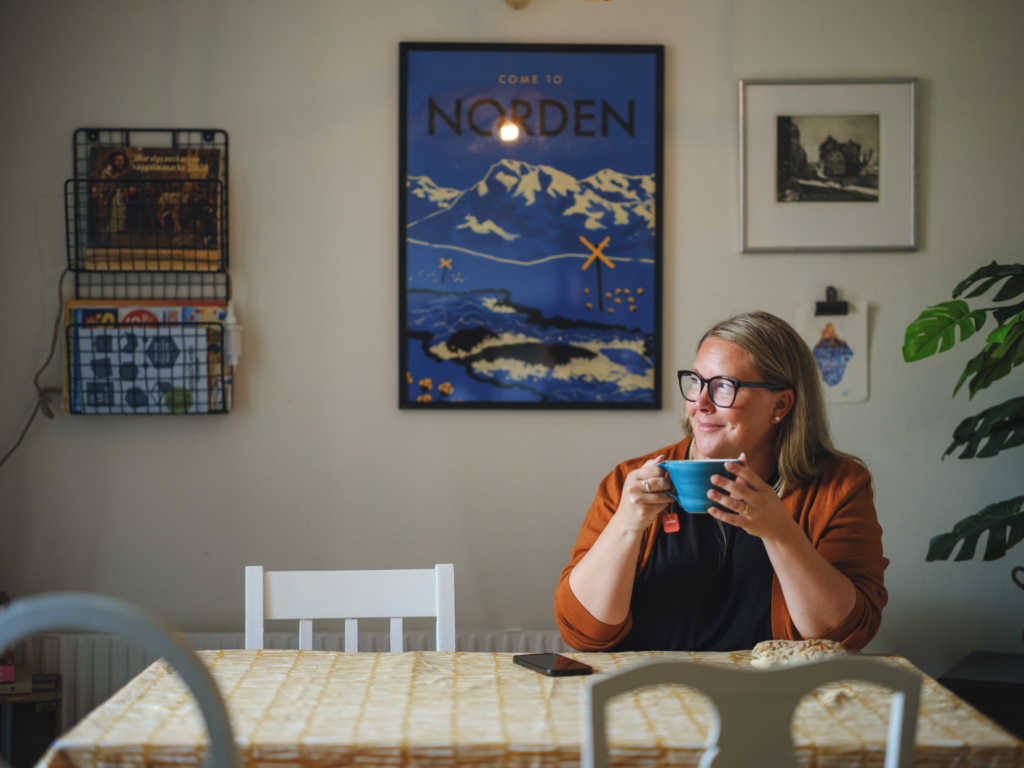 En kvinna sitter vid ett bord och dricker en kopp kaffe.