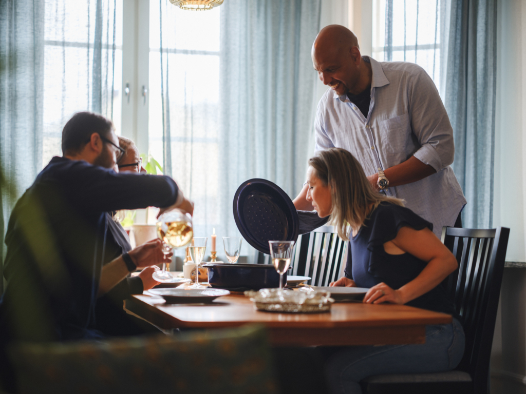 Två kvinnor och två män sitter vid ett matbord och ska äta tillsammans.