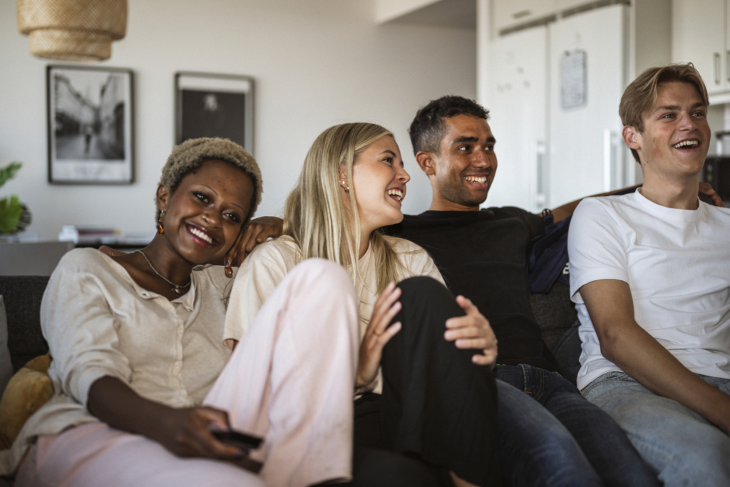 En grupp med ungdomar sitter i en soffa tillsammans.