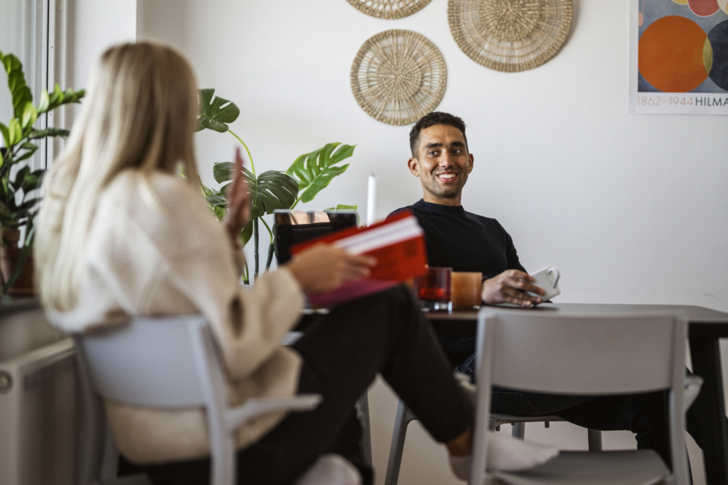 Två unga vuxna sitter vid ett bord och pratar.