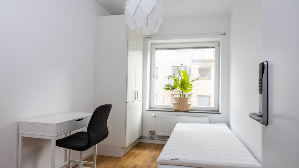 Bo tillsammans-lägenhet: Ett sovrum med en säng, skrivbord och ett fönster.