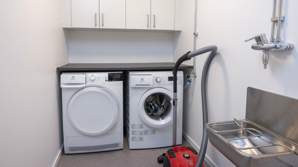 Bo tillsammans-lägenhet: En tvättstuga med tvättmaskin och torktumlare samt tvättho.