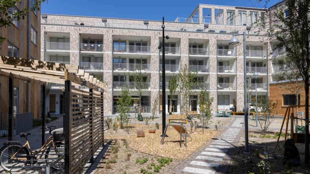 Kanalhuset, fotograferad från innergården. En stor lekplats och cykelställ syns i förgrunden med Kanalhuset i bakgrunden.