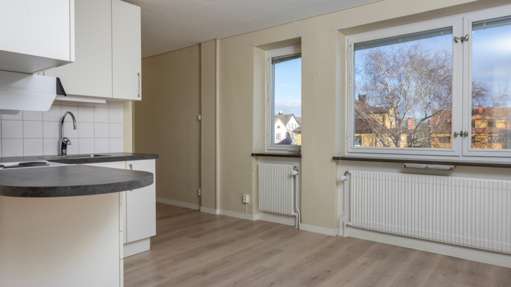 Bild från ett av de egna köken på Assessorn. Ljusa köksluckor och vitt kakel. Stora fönster där man har utsikt över en park.