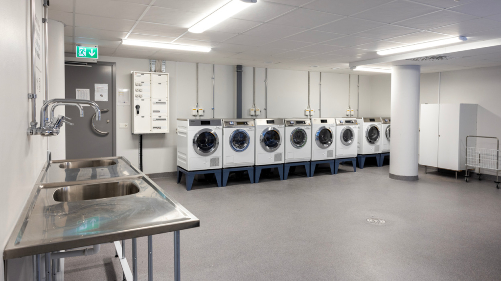 Tvättstugan i Kopparhusen, studentboende. Ett stort utrymme med fyra uppsättningar av tvättmaskin och torktumlare.
